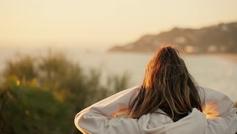 Slow-motion-shot-of-a-female-flicking-he-hair-whilst-watching-the-sunset-over-the-ocean