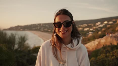 Front-view-of-a-young-Spanish-woman-smiling-at-sunset-with-sea-views