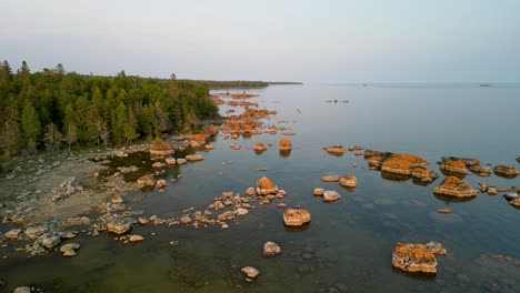 Aerial-ascent-of-boulder-field-along-Lake-Huron-shoreline-and-wilderness,-Upper-Peninsula,-Michigan