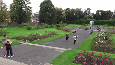 Tourists-taking-photos-in-a-rose-garden-with-fountain-at-Kilkenny-Castle-on-a-warm-summer-morning