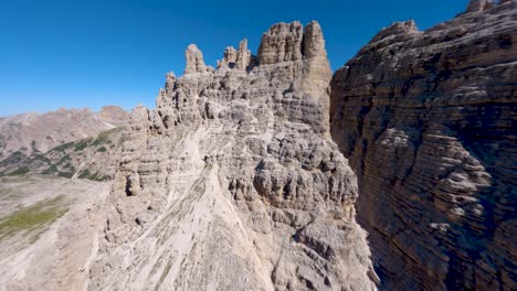 FPV-drone-flying-close-of-the-limestone-rock-wall-revealing-the-famous-Tre-Cime-di-Lavaredo-mountain-at-Dolomites,-Veneto-region,-Italian-Alps