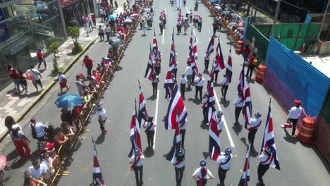 Drone-Shot-Following-School-Children-Hoisting-Costa-Rican-Flag-During-Independence-Day-Parade