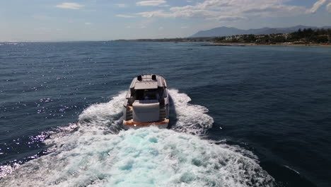 Aerial-view-of-following-a-luxury-yacht-driving-fast-in-sea,-sailing-in-Marbella-Spain,-living-the-good-life,-beautiful-Mediterranian-sea,-jetset-elite-lifestyle,-4K-drone-shot