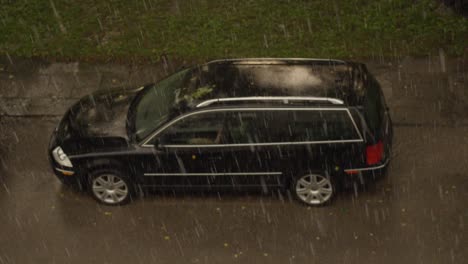 Powerful-rain-hitting-parked-car-in-apartment-building-yard