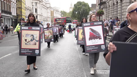 Demonstranten-Marschieren-Durch-Whitehall-Und-Halten-Plakate-In-Der-Hand,-Auf-Denen-Mahsa-Amini-Und-Andere-Menschen-Abgebildet-Sind,-Die-Bei-Frauenrechtsprotesten-Im-Iran-Getötet-Wurden