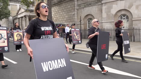 Protesters-march-along-Whitehall-while-holding-black-placards-that-read,-"Woman-Life-Freedom”-during-a-protest-marking-the-death-of-Iranian-Mahsa-Amini,-after-allegedly-violating-hijab-rules