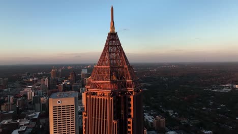 Supertall-skyscraper-Bank-of-America-Plaza-pyramid-like-shape-at-the-top-with-other-skyline-buildings-at-sunset,-Aerial-View