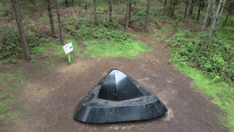 Aerial-view-rising-above-Rendlesham-forest-realistic-flying-saucer-exhibit-on-the-woodland-park-UFO-trail