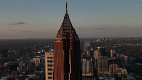 Supertall-skyscraper-Bank-of-America-Plaza-in-the-foreground-with-other-skyline-buildings-in-the-background-at-sunset,-Aerial-View