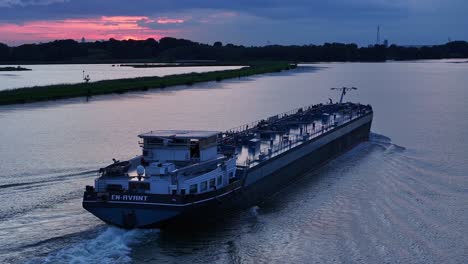 Under-a-dramatic-sunset-the-tanker-En-Avant-sails-on-the-River-Noord,-aerial