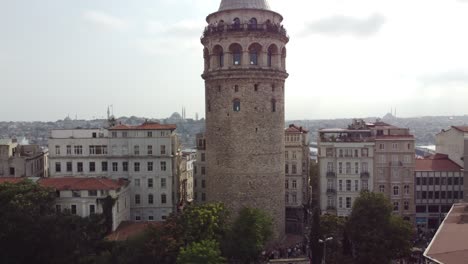 Drone-goes-up-to-reveal-view-of-galata-tower-in-beyoglu-istanbul-with-bosphorus-sea,-mosques,-galata-bridge-in-the-background-behind