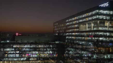 Edificios-Urbanos,-Edificios-De-Cristal-Iluminados-Con-Luz-Nocturna-Al-Atardecer