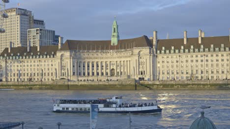 Boat-sailing-along-River-Thames-with-County-Hall-in-background,-London
