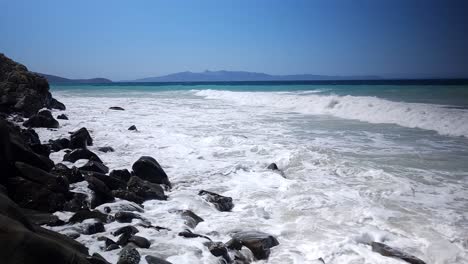 Wavy-Sea-Painted-in-Shades-of-Azure-and-White,-Embracing-the-Rocky-Beach-on-the-Mediterranean-Coastline,-Panoramic-Ionian-Beauty