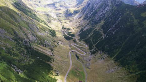 Aerial-high-panoramic-overview-of-Transfagarasan-Serpentine-Road-as-clouds-pass-shadows-over-grassy-landscape