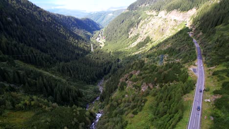 Drone-descends-above-Transfagarasan-Serpentine-Road-showcasing-mountain-river-rushing-through-valley