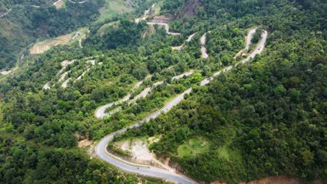 Down-a-steep-mountainous-slope-vehicles-travel-a-winding-road-in-Vietnam
