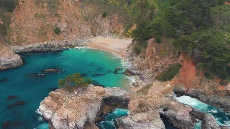 The-cove-in-Julia-Pfeiffer-Burns-State-Park,-California-with-an-aerial-parallax-reveal-of-McWay-Falls