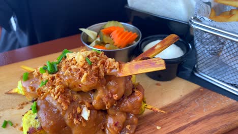 Traditional-Thai-chicken-satay-sticks-with-peanut-sauce-and-fries-in-a-restaurant,-shrimp-chips,-tasty-asian-food,-4K-shot