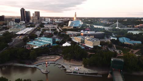 Ein-Abendlicher-Sonnenuntergang,-Goldene-Stunde,-Luftaufnahme-Des-Stadtparks,-Kanadisches-Museum-Für-Menschenrechte,-The-Forks-Market,-Innenstadt-Von-Winnipeg,-Shaw-Park,-Provencher-Bridge,-Red-River-In-Manitoba,-Kanada