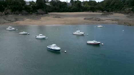Drone-flying-over-boats-moored-on-Dinard-beach-in-France,-Rance-dam