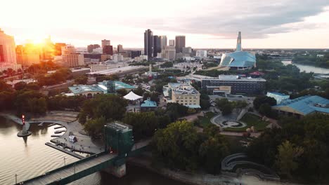 Ein-Sonnenuntergang,-Weite-Goldene-Stunde,-Luftaufnahme-Des-Stadtparks,-Kanadisches-Museum-Für-Menschenrechte,-The-Forks-Market,-Innenstadt-Von-Winnipeg,-Shaw-Park,-Provencher-Bridge,-Red-River-In-Manitoba,-Kanada