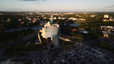 Eine-Orangefarbene-Reflexion,-Sonnenuntergang,-Goldene-Stunde,-Luftaufnahme-Des-Stadtparks,-Kanadisches-Museum-Für-Menschenrechte,-The-Forks-Market,-Innenstadt-Von-Winnipeg,-Shaw-Park,-Provencher-Bridge,-Red-River-In-Manitoba,-Kanada