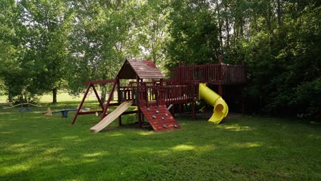 wide-push-in-shot-of-a-kids-jungle-gym-and-swing-set-with-slides-and-swings-in-the-front-yard-of-a-home