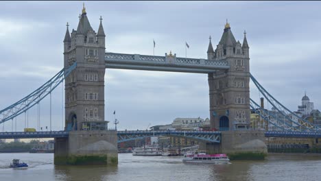 Boats-passing-under-Tower-Bridge-on-cloudy-day,-London