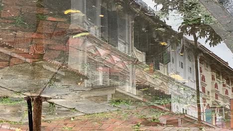 Reflection-in-the-water-of-shophouses-in-Singapore-with-people-walking-by-in-the-daylight