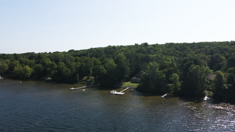 Drone-reverse-dolly-above-private-dock-and-forested-homes-along-hillside-at-lake