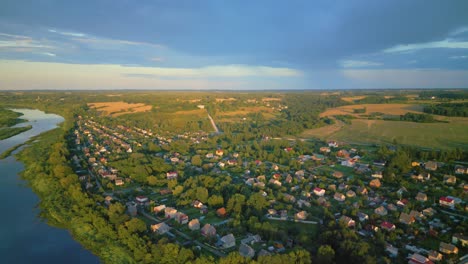 Malerisches-Dorf-Am-Stadtrand-Von-Daugavpils-Am-Ufer-Des-Flusses-Daugava-Bei-Sonnenuntergang,-Umgeben-Von-Viel-Grün,-Luftaufnahme