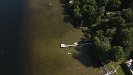 High-angle-bird's-eye-view-of-private-docks-on-shallow-lake-shore-with-dense-tree-canopy