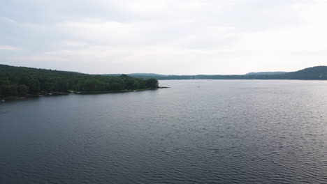 Aerial-panoramic-view-above-maple-lake-ontario-on-cloudy-day,-ripples-spread-across-water