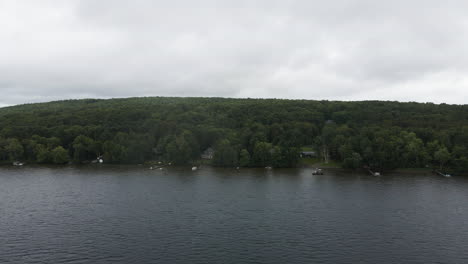 Aerial-pullback-reveals-docks-jutting-into-lake-shore-from-forested-hills-on-cloudy-day