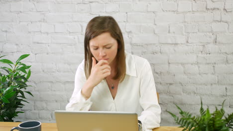 A-young-business-woman-frustrated-working-in-an-office-on-a-laptop