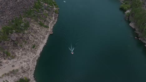 Drone-footage-tracking-a-motor-boat-in-Lake-Kachura,-Skarduu,-Pakistan-beautiful-scene-of-lake-and-mountains-behind