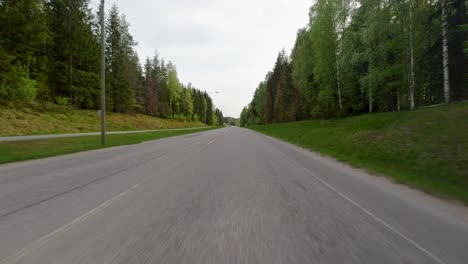 Conduciendo-Rápidamente-Por-Una-Hermosa-Carretera-Finlandesa-Con-Un-Bosque-Verde-A-Ambos-Lados