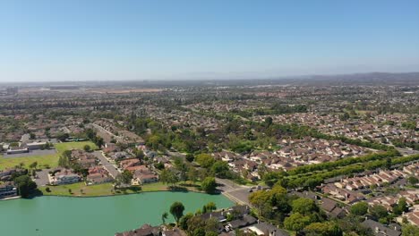 Drone-flying-over-Woodbridge-North-Lake-over-Houses,-with-blue-skies,-green-lake,-and-sunny-2022-summer-day