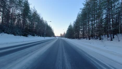 POV-Aufnahmen-Eines-Autos,-Das-An-Einem-Klaren-Morgen-In-Finnland-Schnell-Eine-Verschneite-Landstraße-Entlangfährt