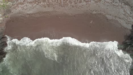 Ocean-Waves-Splashing-On-Sandy-Shore-Of-The-Beach-In-Ballycotton,-County-Cork,-Ireland---aerial-top-down