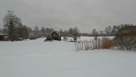 Pan-shot-from-right-to-left-of-wooden-cottages-surrounded-by-snow-all-around-from-snowfall-on-a-cloudy-day