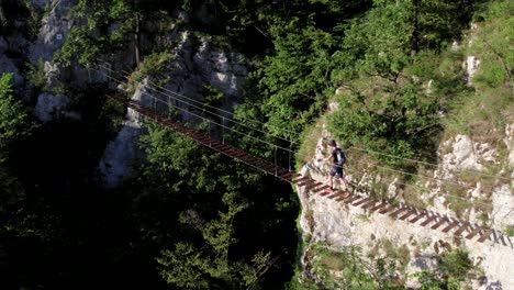 Escalador-Cruzando-Un-Puente-Colgante-De-Madera-En-Una-Vía-Ferrata-En-Las-Montañas-De-Piedra-Caliza