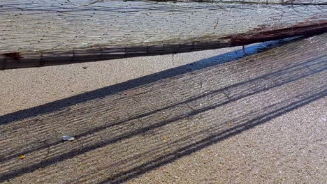 Close-up-of-a-fishing-net-being-pulled-from-the-sea,-in-motion-with-its-shadow-cast-on-the-sand