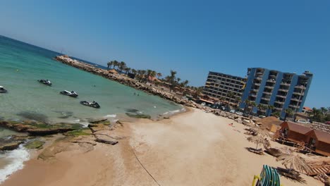 Fpv-flyover-sandy-beach-with-many-Tourist-and-resort-hotel-at-Batroun-City-in-summer,-Lebanon