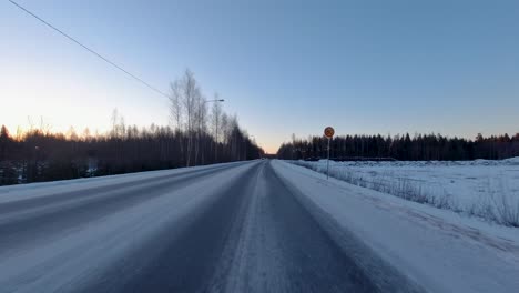 Driving-fast-along-a-snowy-road-flanked-by-trees-during-a-beautiful-winter's-morning-in-Finland
