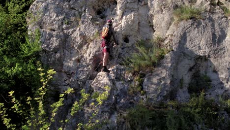 Closeup-of-tourist-climbing-via-ferrata-in-between-foliage-of-trees-during-the-summer