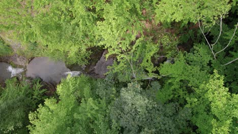 Top-down-view-of-three-waterfalls-after-each-other-that-are-surrounded-by-trees