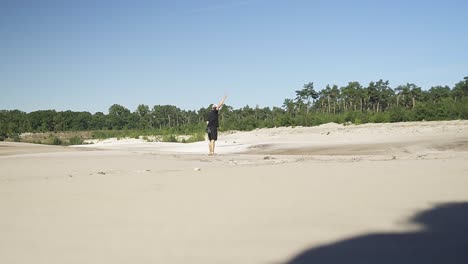 Young-hispanic-male-running-around-and-throwing-stones-at-a-beach-from-a-lake-in-the-belgian-forest
