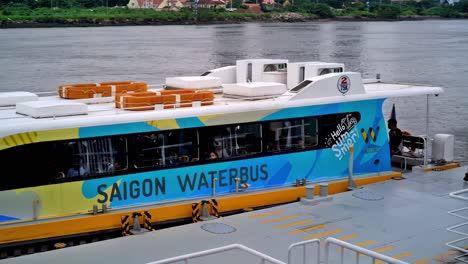A-"waterbus"-awaits-passengers-and-tourists-while-docked-at-one-of-the-stations-along-the-Saigon-River-in-Ho-Chi-Minh-City,-Vietnam